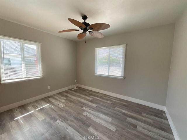 empty room with ceiling fan, a wealth of natural light, and hardwood / wood-style floors