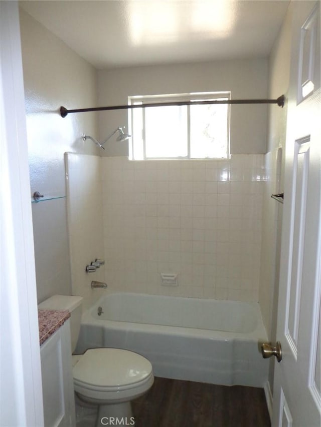 full bathroom featuring hardwood / wood-style floors, toilet, tiled shower / bath, and vanity