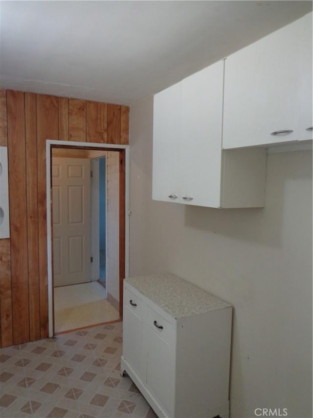 kitchen with wooden walls and white cabinetry