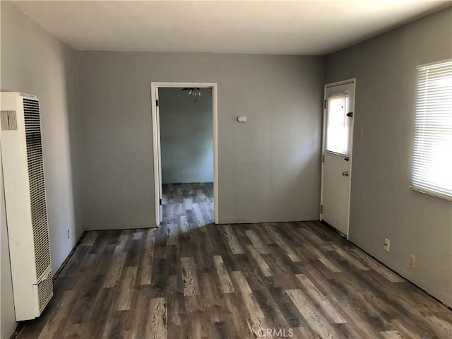 unfurnished room featuring dark wood-type flooring and a healthy amount of sunlight