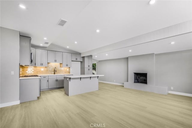 kitchen featuring light hardwood / wood-style floors, gray cabinetry, a center island, and vaulted ceiling