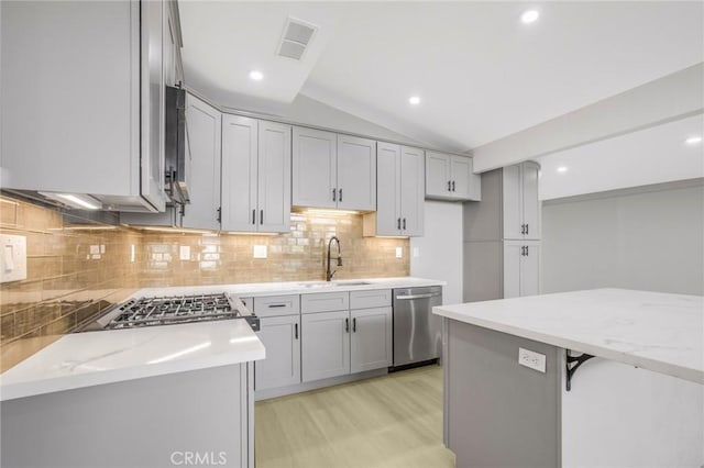 kitchen with dishwasher, sink, vaulted ceiling, light stone counters, and gray cabinets