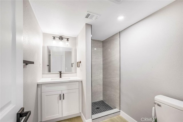 bathroom featuring a tile shower, toilet, and vanity