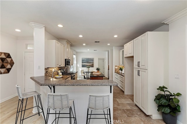 kitchen featuring kitchen peninsula, backsplash, a breakfast bar, and appliances with stainless steel finishes