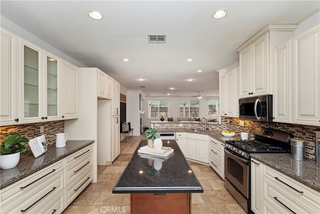 kitchen with a center island, dark stone countertops, kitchen peninsula, backsplash, and stainless steel appliances