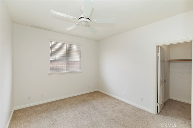 unfurnished bedroom with a closet, ceiling fan, a walk in closet, and light carpet