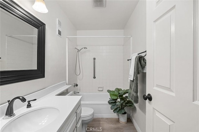 full bathroom with tiled shower / bath combo, hardwood / wood-style flooring, toilet, and vanity