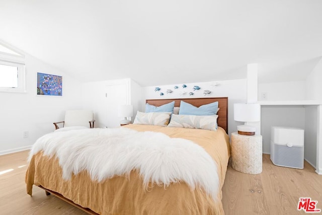 bedroom with light wood-type flooring and lofted ceiling