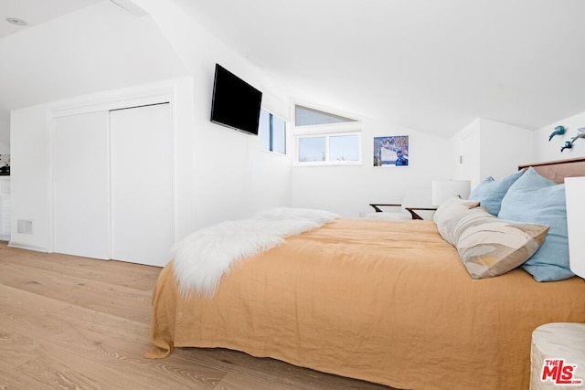 bedroom with lofted ceiling and light wood-type flooring