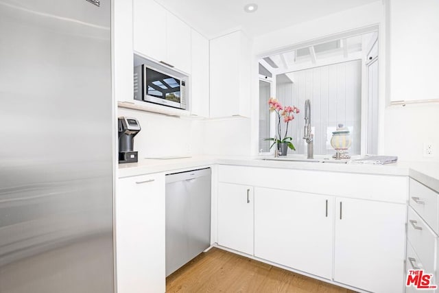 interior space with sink, white cabinets, light wood-type flooring, and stainless steel appliances