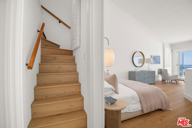 stairs with hardwood / wood-style flooring and vaulted ceiling