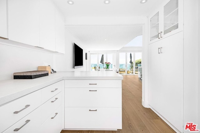 kitchen featuring kitchen peninsula, light wood-type flooring, and white cabinetry