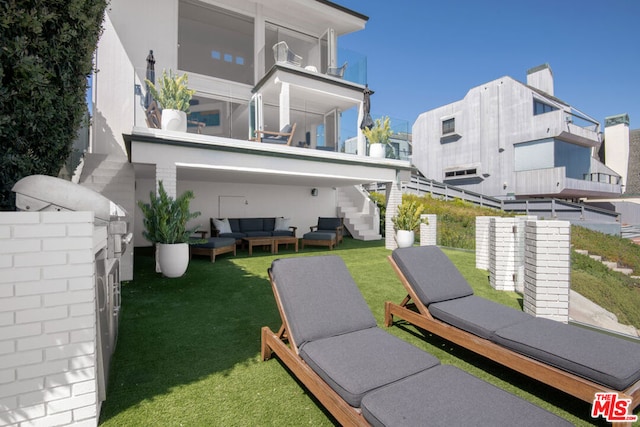 rear view of house featuring a balcony, a yard, and an outdoor hangout area