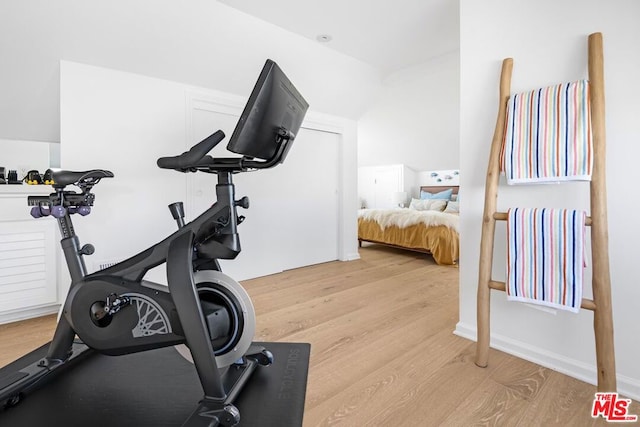 workout room featuring light hardwood / wood-style floors and lofted ceiling