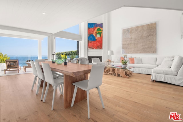 dining area featuring expansive windows, a water view, light hardwood / wood-style flooring, and a fireplace