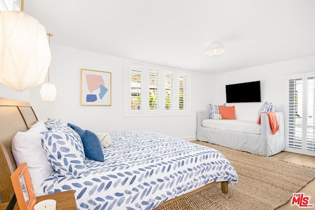 bedroom with multiple windows and hardwood / wood-style flooring