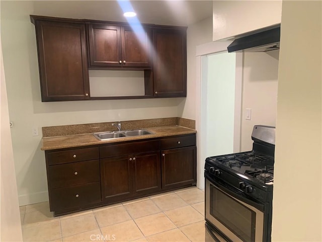 kitchen featuring stainless steel range with gas stovetop, dark brown cabinetry, light tile patterned floors, and sink