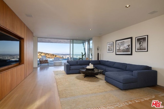 living room with floor to ceiling windows, wooden walls, and light wood-type flooring