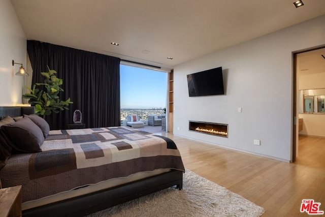 bedroom with hardwood / wood-style flooring, a wall of windows, and ensuite bathroom