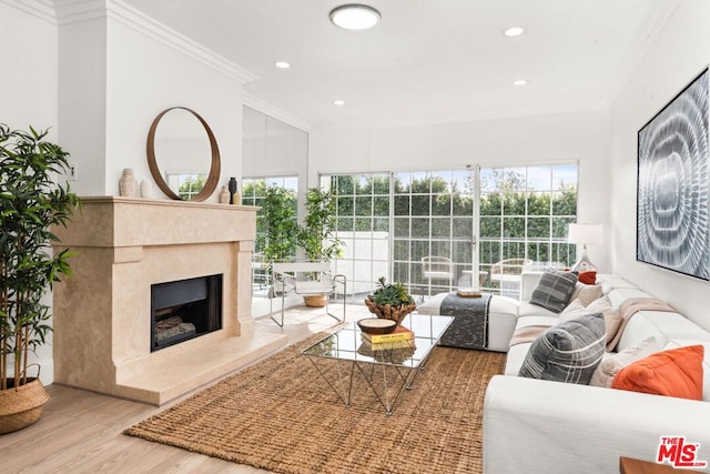 living room featuring hardwood / wood-style flooring, a wealth of natural light, a high end fireplace, and crown molding