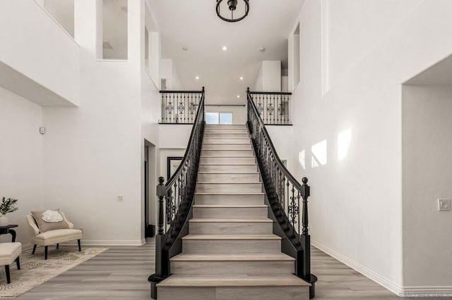 stairway featuring a high ceiling and hardwood / wood-style floors