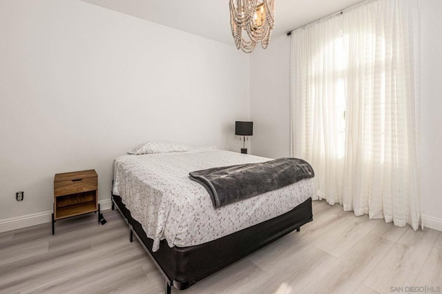 bedroom with hardwood / wood-style flooring and an inviting chandelier