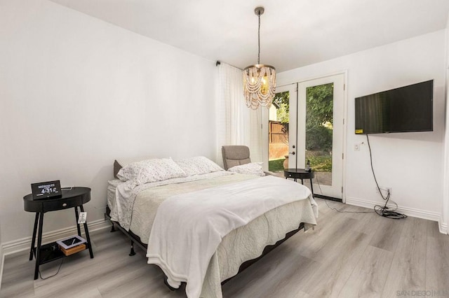 bedroom featuring a notable chandelier, access to exterior, and light hardwood / wood-style floors