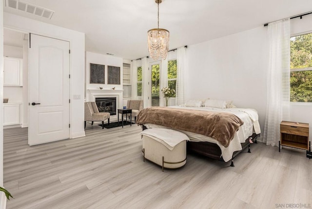 bedroom featuring light wood-type flooring, an inviting chandelier, and multiple windows