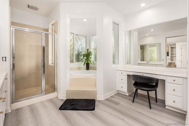 bathroom with wood-type flooring, vanity, and shower with separate bathtub