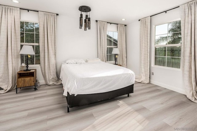 bedroom with multiple windows and light hardwood / wood-style flooring