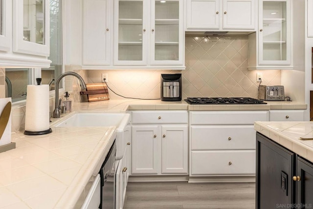 kitchen with white cabinetry, sink, backsplash, light wood-type flooring, and stainless steel gas stovetop