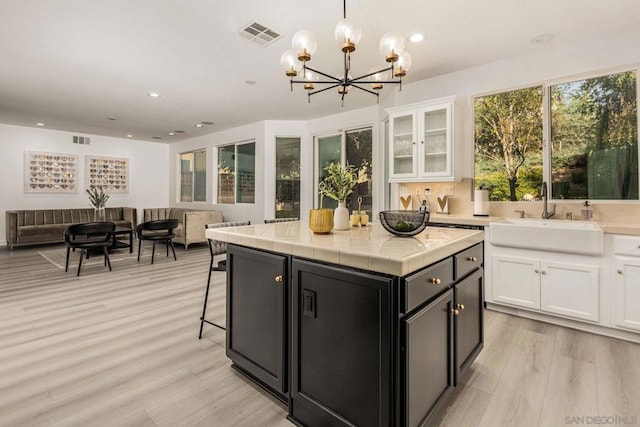 kitchen with sink, white cabinets, a center island, and pendant lighting