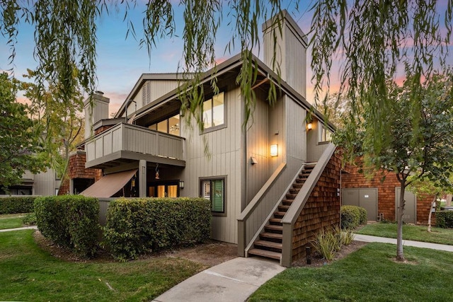 view of front of home featuring a balcony and a yard