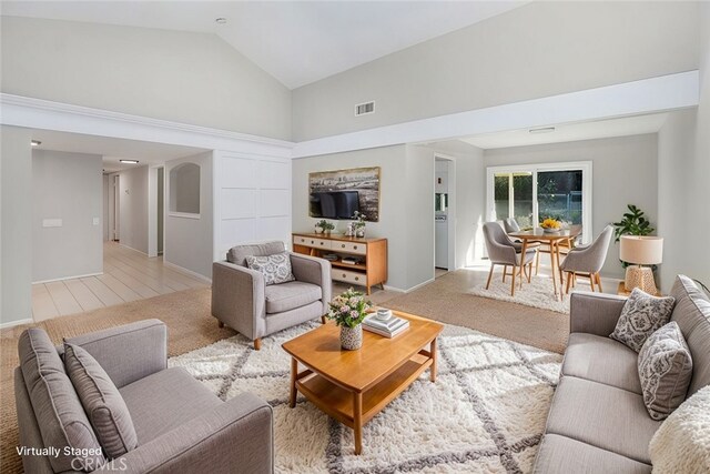 carpeted living room featuring high vaulted ceiling