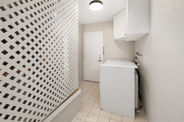 clothes washing area with washer / dryer, cabinets, and light tile patterned flooring