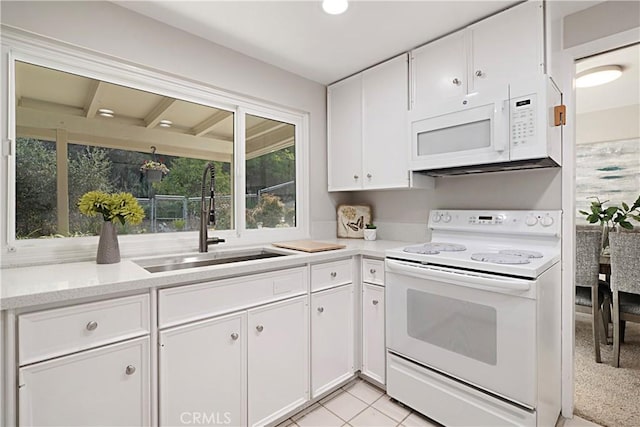 kitchen with sink, light tile patterned floors, white cabinets, and white appliances