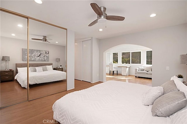 bedroom featuring two closets, ceiling fan, and light wood-type flooring