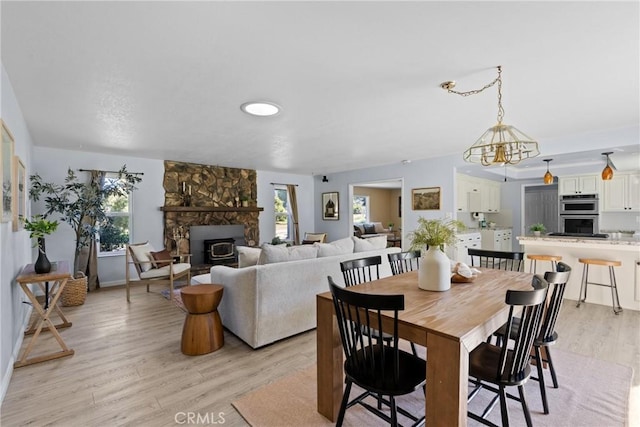 dining area with a wealth of natural light, light hardwood / wood-style flooring, and a stone fireplace