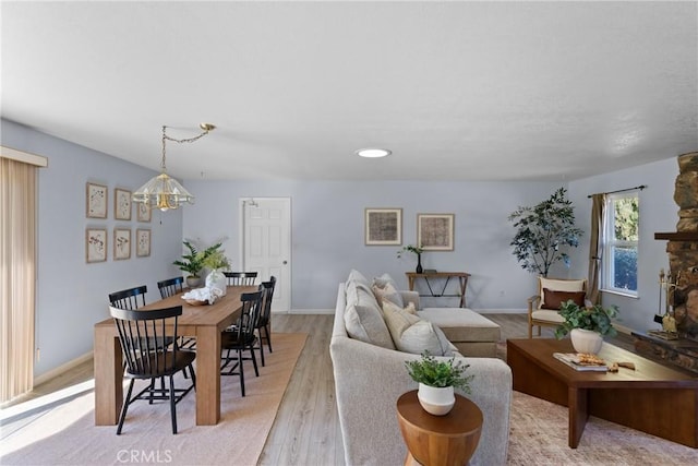 living room with light hardwood / wood-style floors, an inviting chandelier, and a fireplace