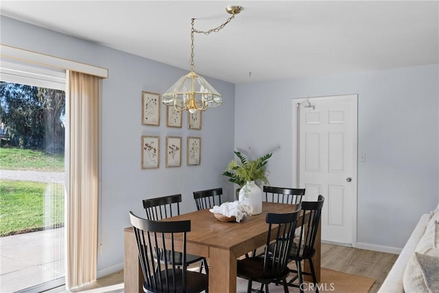 dining space with light hardwood / wood-style flooring and a notable chandelier