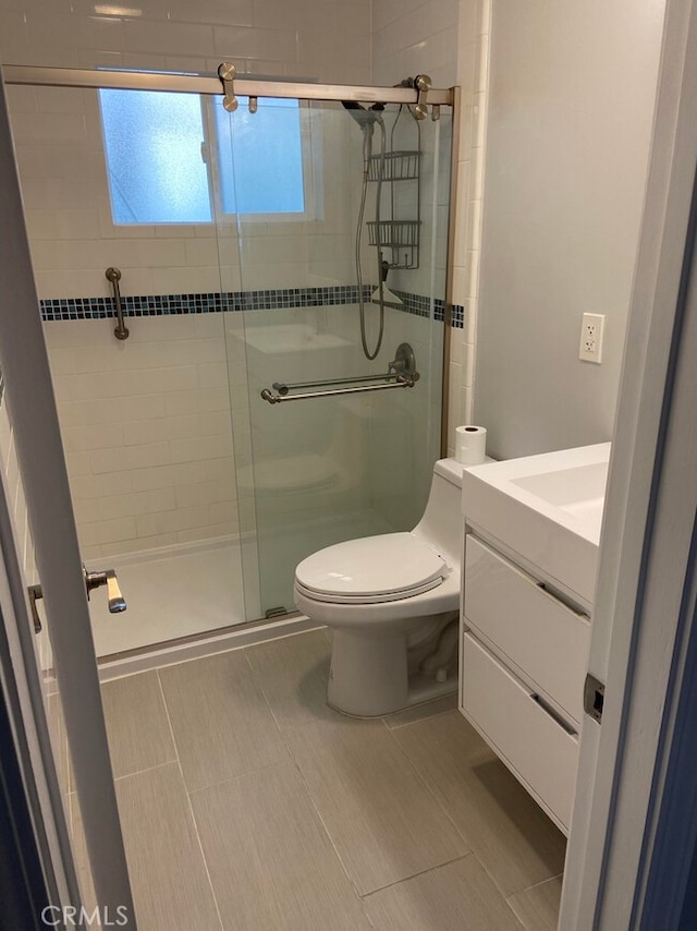 bathroom featuring vanity, toilet, tile patterned floors, and a shower with shower door