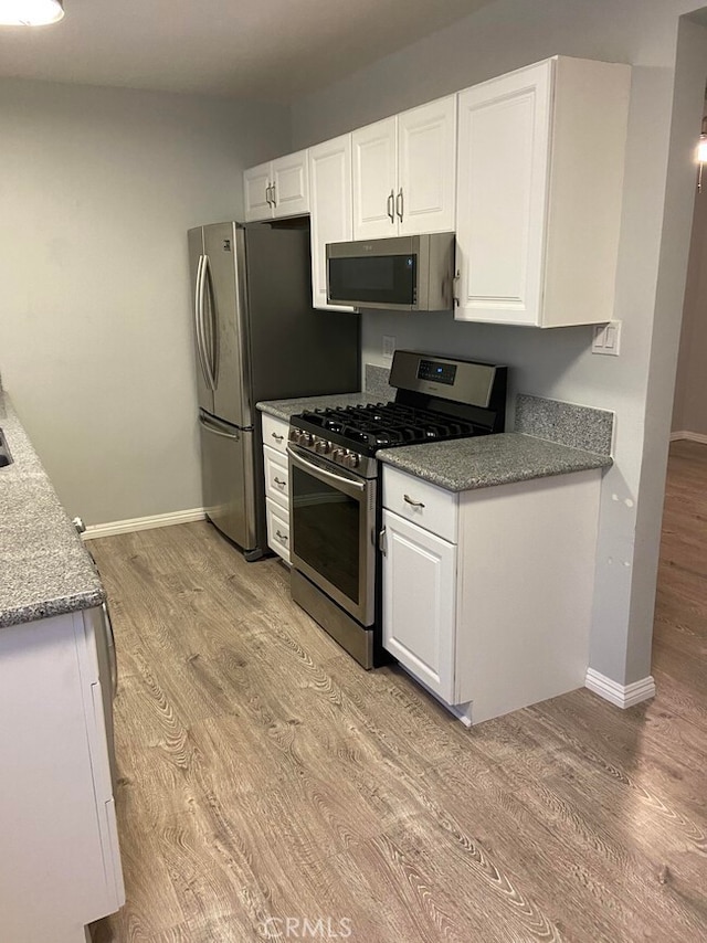 kitchen featuring appliances with stainless steel finishes, light hardwood / wood-style flooring, and white cabinets