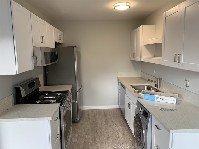 kitchen featuring stainless steel appliances, washer / dryer, white cabinets, and light hardwood / wood-style floors