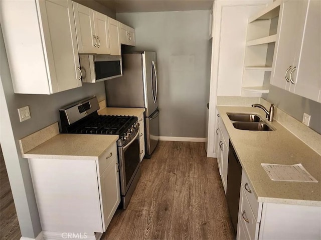 kitchen with appliances with stainless steel finishes, white cabinetry, sink, dark hardwood / wood-style flooring, and light stone counters