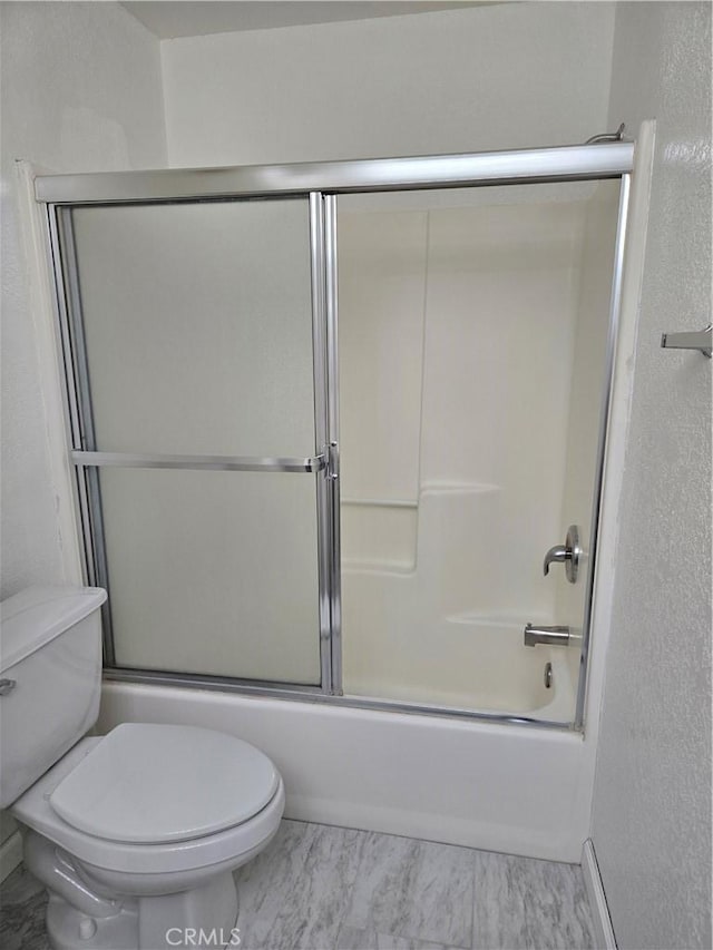 bathroom featuring enclosed tub / shower combo and toilet