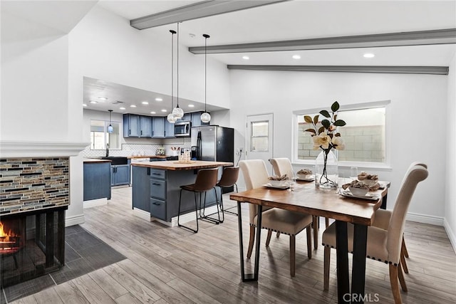 dining room featuring sink, hardwood / wood-style flooring, high vaulted ceiling, and beamed ceiling