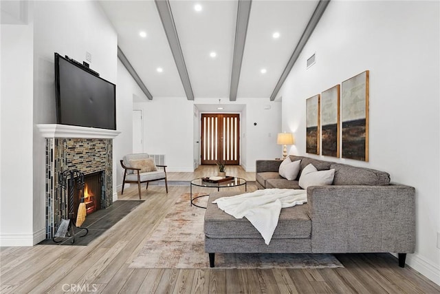 living room with a brick fireplace, lofted ceiling with beams, and hardwood / wood-style floors