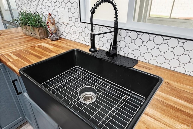 interior details with butcher block countertops, sink, and backsplash