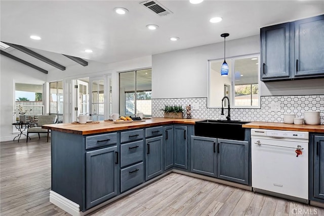 kitchen featuring sink, butcher block counters, hanging light fixtures, lofted ceiling with beams, and decorative backsplash