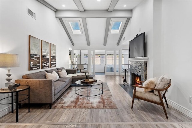 living room featuring beam ceiling, a skylight, high vaulted ceiling, and light hardwood / wood-style flooring